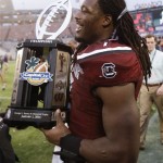 South Carolina defensive end Jadeveon Clowney walks around the field carrying the trophy after South Carolina defeated Wisconsin 34-24 the Capital One Bowl NCAA college football game in Orlando, Fla., Wednesday, Jan. 1, 2014. (AP Photo/John Raoux)