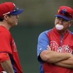 Philadelphia Phillies pitching coach Rich Dubee, right, blows a bubble as he talks with Chase Utley during a workout at baseball spring training, Thursday, Feb. 14, 2013, in Clearwater, Fla. (AP Photo/Matt Slocum)