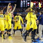 Michigan players including Time Hardaway Jr., right, and Nik Stauskas (11) celebrate after defeating Syracuse in their NCAA Final Four tournament college basketball semifinal game on Saturday, April 6, 2013, in Atlanta. Michigan won 61-56. (AP Photo/Charlie Neibergall)
