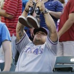 Former Marine Cpl. Zach Briseno, a double amputee, holds up his Texas Rangers-themed prosthetic legs during the seventh-inning stretch at a baseball game between the Rangers and the Arizona Diamondbacks on Thursday, Aug. 1, 2013, in Arlington, Texas. Briseno lost his legs in combat in Iraq. (AP Photo/LM Otero)