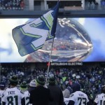 The Vince Lombardi Trophy is displayed on the big screen behind the Seattle Seahawks and a "12th Man" flag on the stage at a rally for NFL football's Super Bowl XLVIII champions in Seattle, Wednesday, Feb. 5, 2014. The Seahawks defeated the Denver Broncos on Sunday. (AP Photo/John Froschauer)