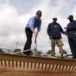 Florida Gov. Rick Scott, left, rakes a field with grounds crew workers Jeff Haag, center, and Anthony Melton, right, during a work day before a baseball spring training exhibition game between the Detroit Tigers and the Atlanta Braves, Wednesday, Feb. 27, 2013, in Lakeland, Fla. (AP Photo/Charlie Neibergall)