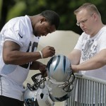 Carolina Panthers' Kawaan Short, left, signs an autograph for Brian Clark, right, , during an NFL football rookie camp in Charlotte, N.C., Saturday, May 11, 2013. (AP Photo/Chuck Burton)
