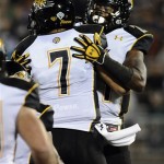 Towson quarterback Peter Athens (7) celebrates with Towson line backer Sterlin Phifer after Phifer scored a touchdown during the first half of an NCAA college football game at Rentschler Field in East Hartford, Conn., Thursday, Aug. 29, 2013. (AP Photo/Jessica Hill)