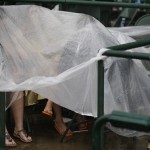 Megan Grable, left, from St. Louis, Mo., and Cindy Brenner, of Louisville, Ky., wait under a plastic tarp for the next race during the 139th Kentucky Derby at Churchill Downs Saturday, May 4, 2013, in Louisville, Ky. (AP Photo/David Goldman)
