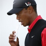 Tiger Woods of the United States puts a map of pin positions between his teeth as he walks off the 6th green during the final round of the British Open Golf Championship at Muirfield, Scotland, Sunday, July 21, 2013. (AP Photo/Matt Dunham)
