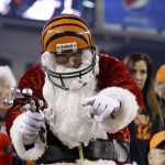 A Cincinnati Bengals fan dressed in a Santa Claus outfit cheers during the first half of an NFL football game between the Bengals and the Denver Broncos on Monday, Dec. 22, 2014, in Cincinnati. (AP Photo/Michael Conroy)
