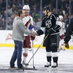NASCAR driver Kevin Harvick, left, shakes hands with Los Angeles Kings right wing Dustin Brown, right, and Arizona Coyotes right wing Shane Doan, center, after dropping the ceremonial first puck before the first period of an NHL hockey game, Monday, March 16, 2015, in Los Angeles. (AP Photo/Danny Moloshok)