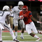 Arizona running back Nick Wilson (28) rns between two Nevada defenders during the first half of the NCAA college football game, Saturday, Sept. 13, 2014, in Tucson, Ariz. (AP Photo/Rick Scuteri)