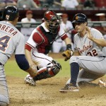 Detroit Tigers' Don Kelly (32) scores a run ahead of the tag by Arizona Diamondbacks' Miguel Montero, middle, as Tigers' Miguel Cabrera (24) looks on during the eighth inning of a baseball game on Tuesday, July 22, 2014, in Phoenix. (AP Photo)