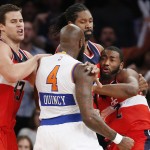 Washington Wizards forwards Kris Humphries, left, and Nene Hilario (42) restrain New York Knicks forward Quincy Acy (4) who has his hand balled into a fist, and Wizards guard John Wall (2) after Acy and Wall engaged in an on-court scuffle in the second half of an NBA basketball game at Madison Square Garden in New York, Thursday, Dec. 25, 2014. Acy was ejected from the game. Wall was assessed a technical foul. The Wizards defeated the Knicks 102-91. (AP Photo/Kathy Willens)