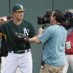 Actor Will Ferrell, left, warms up for the Oakland Athletics prior to the first inning of a spring training baseball game against the Seattle Mariners, Thursday, March 12, 2015, in Mesa, Ariz. The comedian plans to play every position while making appearances at five Arizona spring training games on Thursday. (AP Photo/Matt York)
