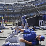 Toronto Blue Jays' Jose Bautista, foreground, stretches on a tarp before an opening day baseball game against the New York Yankees in New York, Monday, April 6, 2015. (AP Photo/Kathy Willens)