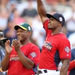 Minnesota Vikings running back Adrian Peterson, right, and former Oakland A's baseball player Rickey Henderson react to the crowd before the All-Star Legends & Celebrity Softball Game, Sunday, July 13, 2014, in Minneapolis. (AP Photo/Jim Mone)