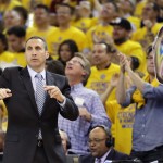 Cleveland Cavaliers head coach David Blatt gestures as a fan holds up a large photo of Golden State Warriors guard Stephen Curry during the first half of Game 1 of basketball's NBA Finals between the Warriors and the Cavaliers in Oakland, Calif., Thursday, June 4, 2015. (AP Photo/Ben Margot)