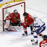 A puck sails over Chicago Blackhawks goalie Corey Crawford, left, teammate Duncan Keith, center, and Tampa Bay Lightning's Steven Stamkos, right, during the second period in Game 6 of the NHL hockey Stanley Cup Final series on Monday, June 15, 2015, in Chicago. (AP Photo/Charles Rex Arbogast)