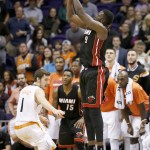 Miami Heat's Luol Deng (9) shoots a 3-pointer as Phoenix Suns' Goran Dragic (1) defends during the second half of an NBA basketball game Tuesday, Dec. 9, 2014, in Phoenix. Deng made the shot and the Heat defeated the Suns 103-97. (AP Photo/Ross D. Franklin)