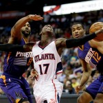 Atlanta Hawks' Dennis Schroder, of Germany, center, loses the ball while dribbling against the defense of Phoenix Suns' Jerel McNeal, left, and T.J. Warren in the first quarter of an NBA basketball game Tuesday, April 7, 2015, in Atlanta. (AP Photo/David Goldman)