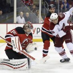 New Jersey Devils goaltender Cory Schneider, left, gloves the puck as Devils' Peter Harrold checks Arizona Coyotes' Martin Erat, right, during the first period of an NHL hockey game Monday, Feb. 23, 2015, in Newark, N.J. (AP Photo/Bill Kostroun)