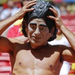 An Argentina supporter adjusts his Diego Maradona mask before the start of the World Cup quarterfinal soccer match between Argentina and Belgium at the Estadio Nacional in Brasilia, Brazil, Saturday, July 5, 2014. (AP Photo/Frank Augstein)