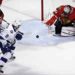 Chicago Blackhawks goalie Corey Crawford, right, deflects a shot as Tampa Bay Lightning's Tyler Johnson, left, watches during the first period in Game 6 of the NHL hockey Stanley Cup Final series on Monday, June 15, 2015, in Chicago. (AP Photo/Charles Rex Arbogast)
