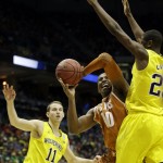  Texas forward Jonathan Holmes (10) drives the ball against Michigan guard Caris LeVert as Michigan guard Nik Stauskas (11) watches during the second half of a third-round game of the NCAA college basketball tournament Saturday, March 22, 2014, in Milwaukee. (AP Photo/Morry Gash)
