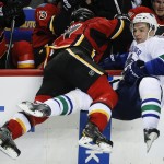 Vancouver Canucks' Radim Vrbata, right, is checked into the boards Calgary Flames' Lance Bouma during second period NHL hockey action in Calgary, Alberta, Wednesday, Oct. 8, 2014. (AP Photo/The Canadian Press, Jeff McIntosh)