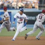 Los Angeles Dodgers' Justin Turner runs towards third base on a single by Adrian Gonzalez while Arizona Diamondbacks third baseman Jake Lamb, left, and shortstop Nick Ahmed, right, run into position during the first inning of a baseball game Monday, June 8, 2015, in Los Angeles. (AP Photo/Danny Moloshok)
