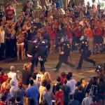 Tucson Police Officers rush out of their line to take a man into custody who had been taunting them and riling up a crowd of fans in Maingate Square, Saturday, March 29, 2014, in Tucson Ariz. following Arizona's loss to Wisconsin 64-63 in the West Region NCAA final. (AP Photo/Arizona Daily Star, Kelly Presnell) 