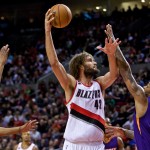Portland Trail Blazers center Robin Lopez, center, shoots over Phoenix Suns forward P.J. Tucker, right, and forward Markieff Morris, left, during the third quarter of an NBA basketball game in Portland, Ore., Monday, March 30, 2015. (AP Photo/Craig Mitchelldyer)