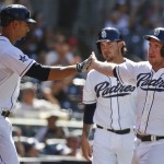 San Diego Padres' Jedd Gyorko, right, is congratulated by Tyson Ross after he and Yasmani Grandal, rear, scored on a single by Corey Spangenberg in the fifth inning of a baseball game, Monday, Sept. 1, 2014, in San Diego. (AP Photo/Lenny Ignelzi)
