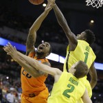 Oklahoma State forward Michael Cobbins is fouled by Oregon forward Jordan Bell (1) while driving to the basket during the first half of an NCAA tournament college basketball game in the Round of 64, Friday, March 20, 2015, in Omaha, Neb. Oregon guard Casey Benson (2) looks on. (AP Photo/Charlie Neibergall)