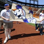 Robert Hermida, left, and son, Andrew of Brick, New Jersey walk the warning track with their banner on Banner Day before the baseball game at Citi Field on Sunday, May 25, 2014, in New York. (AP Photo/Kathy Kmonicek)