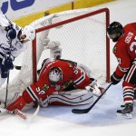 Chicago Blackhawks goalie Corey Crawford (50) reaches for a loose puck as teammate Johnny Oduya (27), of Sweden, and Tampa Bay Lightning's Brenden Morrow watch during the second period in Game 6 of the NHL hockey Stanley Cup Final series on Monday, June 15, 2015, in Chicago. (AP Photo/Charles Rex Arbogast)