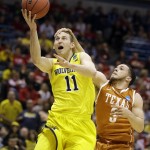  Michigan guard Nik Stauskas (11) is fouled by Texas guard Javan Felix (3) during the second half of a third-round game of the NCAA college basketball tournament Saturday, March 22, 2014, in Milwaukee. (AP Photo/Jeffrey Phelps)