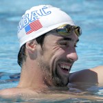 Michael Phelps laughs while talking with coaches during a training session Wednesday, April 23, 2014, in Mesa, Ariz., as he prepares to compete for the first time since retiring after the 2012 London Games. The 22-time Olympic medalist is entered in three events at the Arena Grand Prix starting Thursday. (AP Photo/Matt York)