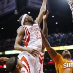 Houston Rockets' Corey Brewer (33) jumps between Phoenix Suns' Isaiah Thomas, left, and P.J. Tucker, right, to tip the ball in during the first half of an NBA basketball game Friday, Jan. 23, 2015, in Phoenix. (AP Photo/Ross D. Franklin)