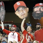 St. Louis Cardinals fans hold up cutouts of players' faces before a baseball game between the Arizona Diamondbacks and the Cardinals, Sunday, Sept. 28, 2014, in Phoenix. The Cardinals won the NL Central with a Pittsburgh Pirates loss earlier in the day. (AP Photo/Rick Scuteri)