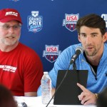 Michael Phelps, right, speaks to the media after practice as coach Bob Bowman listens Wednesday, April 23, 2014, in Mesa, Ariz. Phelps is competing in the Arena Grand Prix at Mesa on Thursday as he returns to competitive swimming after a nearly two-year retirement. (AP Photo/Matt York)