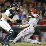 Arizona Diamondbacks' Paul Goldschmidt scores while Seattle Mariners catcher Mike Zunino waits for the throw on a sacrifice fly hit by Diamondbacks' Jake Lamb during the tenth inning of a baseball game on Monday, July 27, 2015, in Seattle. (AP Photo/John Froschauer)