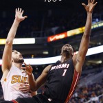 Miami Heat's Chris Bosh (1) shoots the ball past Phoenix Suns' Miles Plumlee, left, for a score during the first half of an NBA basketball game Tuesday, Dec. 9, 2014, in Phoenix. (AP Photo/Ross D. Franklin)