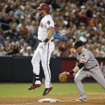 Arizona Diamondbacks' David Peralta, left, jumps off of third base in celebration of his run-scoring triple as San Francisco Giants' Matt Duffy, right, reaches out to apply a late tag during the third inning of a baseball game Friday, July 17, 2015, in Phoenix. (AP Photo/Ross D. Franklin)
