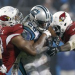 Carolina Panthers' Jonathan Stewart, center, is tackled by Arizona Cardinals' Marcus Benard, right, and Calais Campbell, left, in the second half of an NFL wild card playoff football game in Charlotte, N.C., Saturday, Jan. 3, 2015. (AP Photo/Bob Leverone)