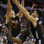 Phoenix Suns' Alex Len, left, and Phoenix Suns' Devin Booker, right, grab for a rebound over San Antonio Spurs' Shannon Scott during the first half of an NBA summer league basketball game Monday, July 20, 2015, in Las Vegas. (AP Photo/John Locher)
