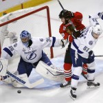 Chicago Blackhawks' Jonathan Toews, center, avoids Tampa Bay Lightning's Valtteri Filppula, of Finland, as Lightning goalie Ben Bishop, left, deflects a puck during the first period in Game 6 of the NHL hockey Stanley Cup Final series on Monday, June 15, 2015, in Chicago. (AP Photo/Charles Rex Arbogast)
