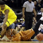  Michigan guard Derrick Walton Jr., left, and Texas forward Jonathan Holmes chase after a loose ball during the second half of a third-round game of the NCAA college basketball tournament Saturday, March 22, 2014, in Milwaukee. (AP Photo/Jeffrey Phelps)