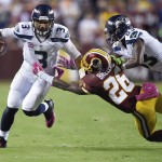 Seattle Seahawks quarterback Russell Wilson (3) escapes the grasp of Washington Redskins strong safety Bashaud Breeland (26) during the first half of an NFL football game in Landover, Md., Monday, Oct. 6, 2014. (AP Photo/Nick Wass)