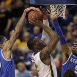 Wichita State's Chadrack Lufile (0) shoots under pressure from Kentucky's Willie Cauley-Stein (15) and Andrew Harrison (5) during the first half of a third-round game at the NCAA college basketball tournament Sunday, March 23, 2014, in St. Louis. (AP Photo/Charlie Riedel)