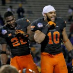 Oklahoma State running back and offensive player of the game Desmond Roland, left, and linebacker and defensive player of the game, Seth Jacobs (10) react to their teammates after the Cactus Bowl NCAA college football game, Friday, Jan. 2, 2015, in Tempe, Ariz. Oklahoma State won 30-22. (AP Photo/Matt York)