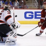 New Jersey Devils' Cory Schneider, left, makes a save on a shot by Arizona Coyotes' Joe Vitale (14) during the second period of an NHL hockey game Saturday, March 14, 2015, in Glendale, Ariz. (AP Photo/Ross D. Franklin)